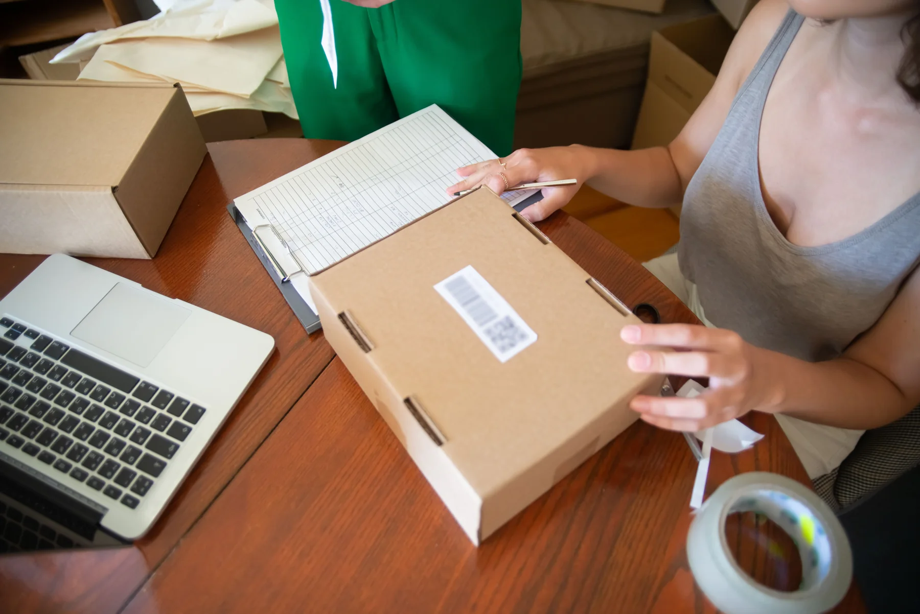 Ecommerce operator preparing a customer shipment beside a laptop